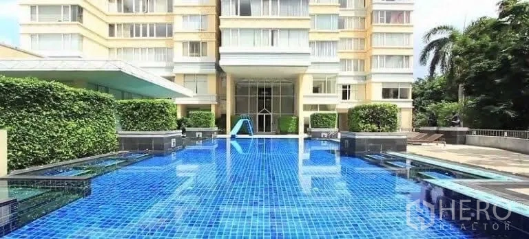 Condominium for rent in Watthana, Bangkok - Condominium outdoor swimming pool with blue tiles and landscaped greenery at the entrance.