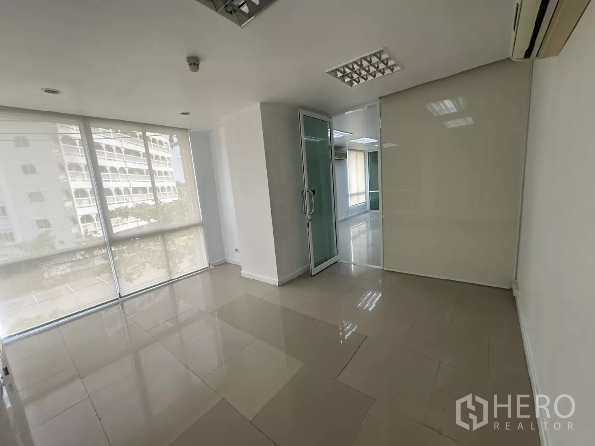 Office Space for rent in Huai Khwang, Bangkok - Light-filled corner office with floor-to-ceiling windows, roller shades and a glass door.