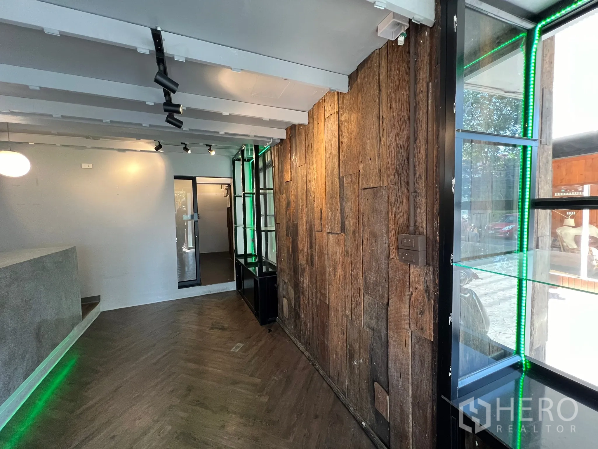 Retail Space for rent in Watthana, Bangkok - Close-up of showroom aisle featuring a rustic timber feature wall, glass display shelving and track lighting.