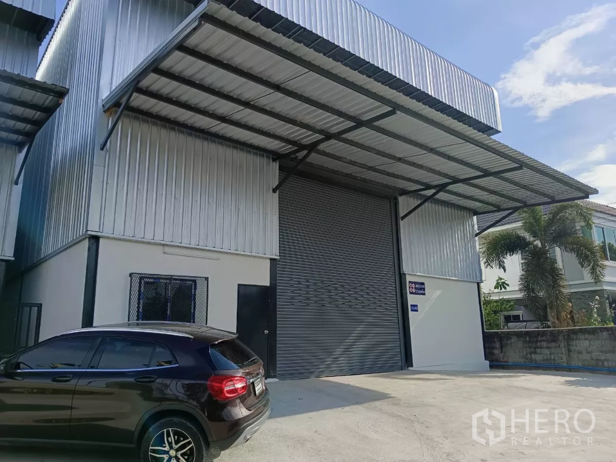 Warehouse for rent in Bang Phli, Samut Prakan - Newly built warehouse exterior in Bang Phli with wide roller shutter, canopy and parking area.