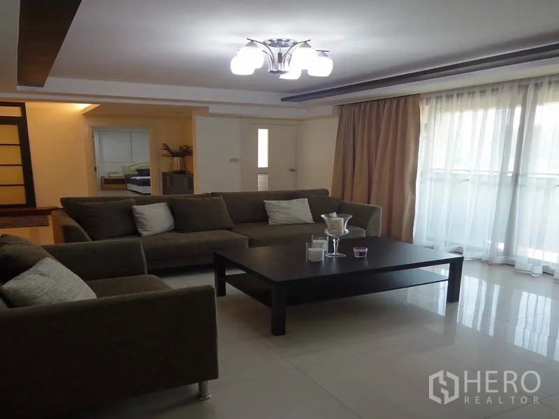 Condominium for rent in Watthana, Bangkok - Lounge with sectional sofa, coffee table and full-height curtains.