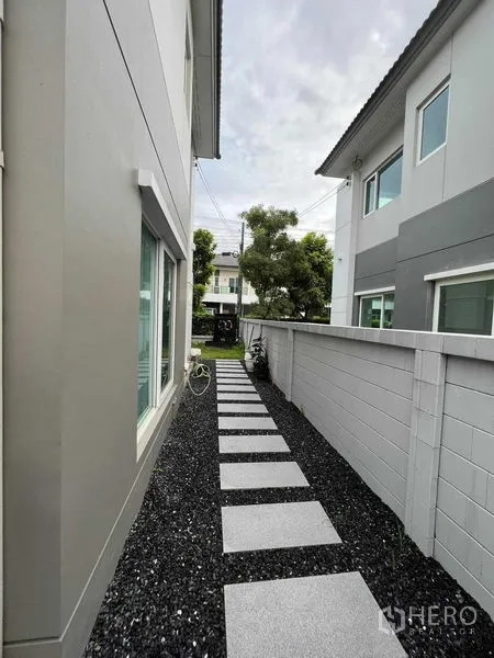 独立式住宅 出租或出售在Lat Krabang, Bangkok - 前草坪与房屋立面，带大遮阳篷和车棚。