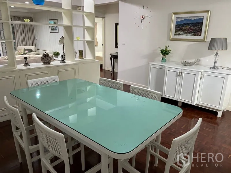 Apartment for rent in Watthana, Bangkok - Dining space with a glass-top table for six and a white sideboard.
