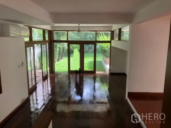 บ้าน ให้เช่าในWatthana, Bangkok - ห้องนั่งเล่นสว่างด้วยผนังกระจกสูง มองเห็นสวน