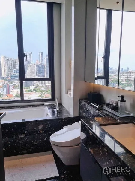 Condominium for sale - Bathroom with soaking tub and wide city skyline view through a large window.
