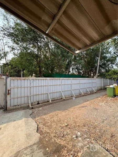 คลังสินค้า ขายในBang Bua Thong, Nonthaburi - ลานบริการข้างประตูเลื่อนโลหะ รั้วรอบขอบชิดและต้นไม้.