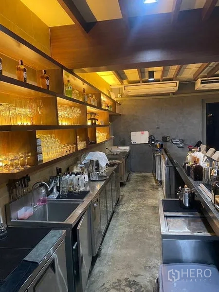 Shophouse for rent - Back-of-bar workspace with sinks, undercounter fridges, and glassware on lit shelves.