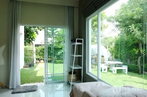 บ้าน ขายในMin Buri, Bangkok - ห้องนั่งเล่นสว่างด้วยหน้าต่างมุมกว้างและประตูกระจก มองเห็นสวนสีเขียว