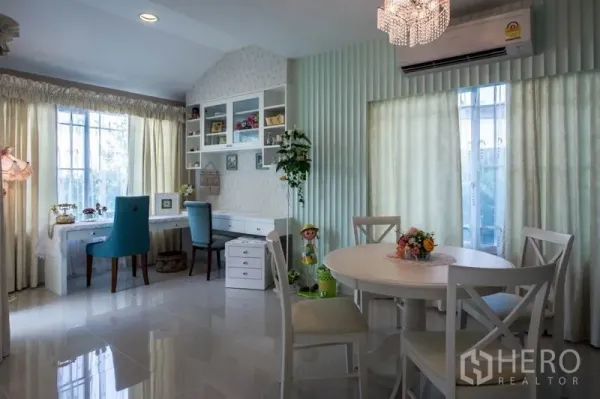 Detached House for sale in Bang Kapi, Bangkok - Bright dining and study area with a round table, built-in shelves and large curtained windows.