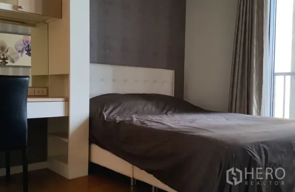 คอนโด ให้เช่าในSathon, Bangkok - ห้องนอนที่สาม ผนังเน้นสีเข้ม โต๊ะทำงานพร้อมแผงลายดอกไม้ และหน้าต่างเปิดสู่ระเบียง