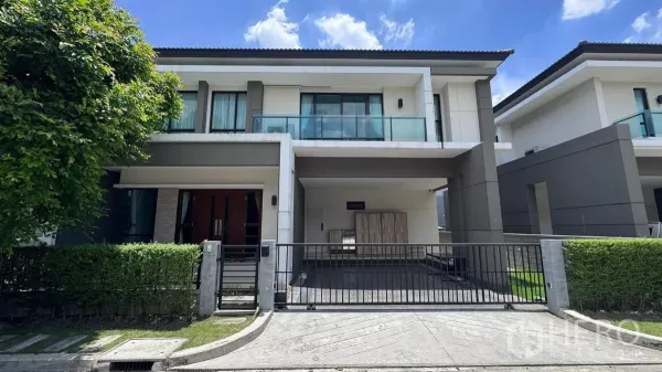 独立式住宅 出租或出售在Saphan Sung, Bangkok - 曼谷沙攀颂现代两层独栋外观，入户铁门、车棚与玻璃阳台，绿篱环绕，天空晴朗。