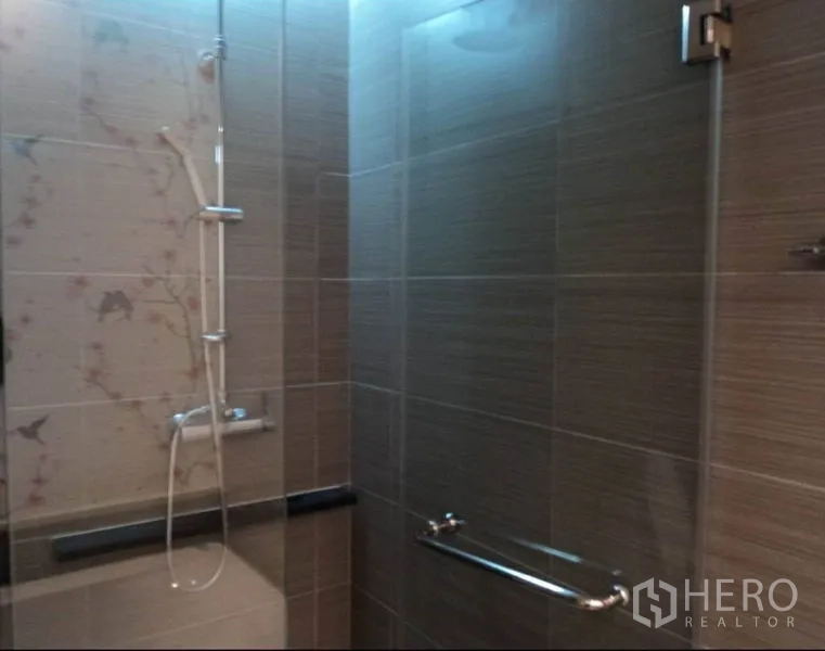 Condominium for rent in Khlong Toei, Bangkok - Glass-enclosed shower with handheld shower set and neutral tiled walls.