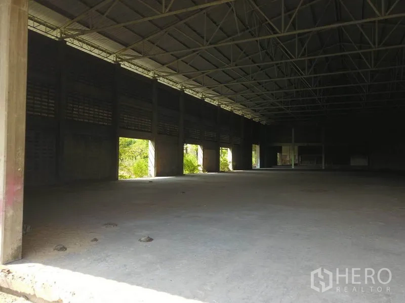 Factory for sale in Samut Prakan - Interior of a wide-span factory hall with steel truss roof and concrete floor.