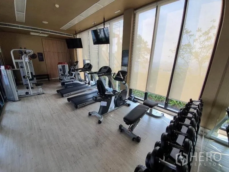 公寓 出售在Ratchathewi, Bangkok - 公寓健身房，配有跑步机、动感单车、力量器械和落地窗。