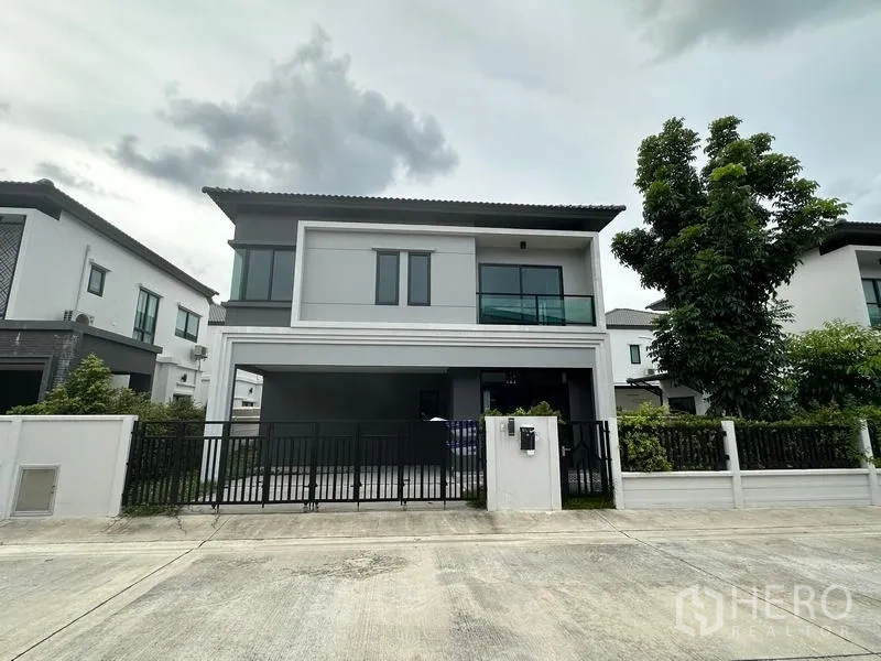 独立式住宅 出售在Khlong Sam Wa, Bangkok - 现代两层独栋别墅正立面，带黑色大门与车道