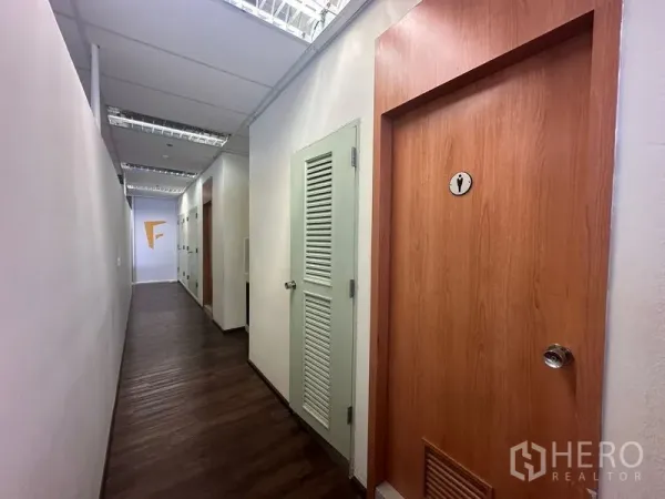 Office Space for rent in Bang Rak, Bangkok - Office hallway featuring a restroom door and louvered storage cupboards.
