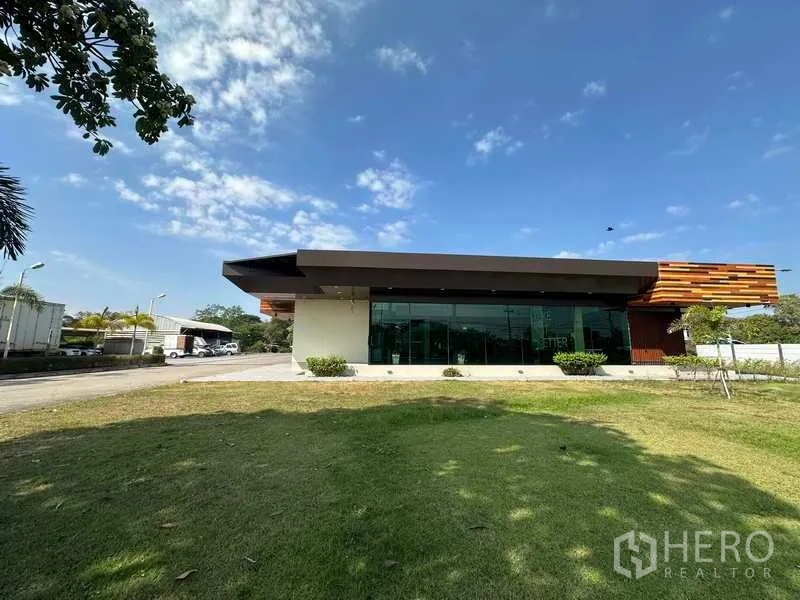 Warehouse for rent in Lam Luk Ka, Pathum Thani - Front view of modern office pavilion with large windows and grassed frontage.