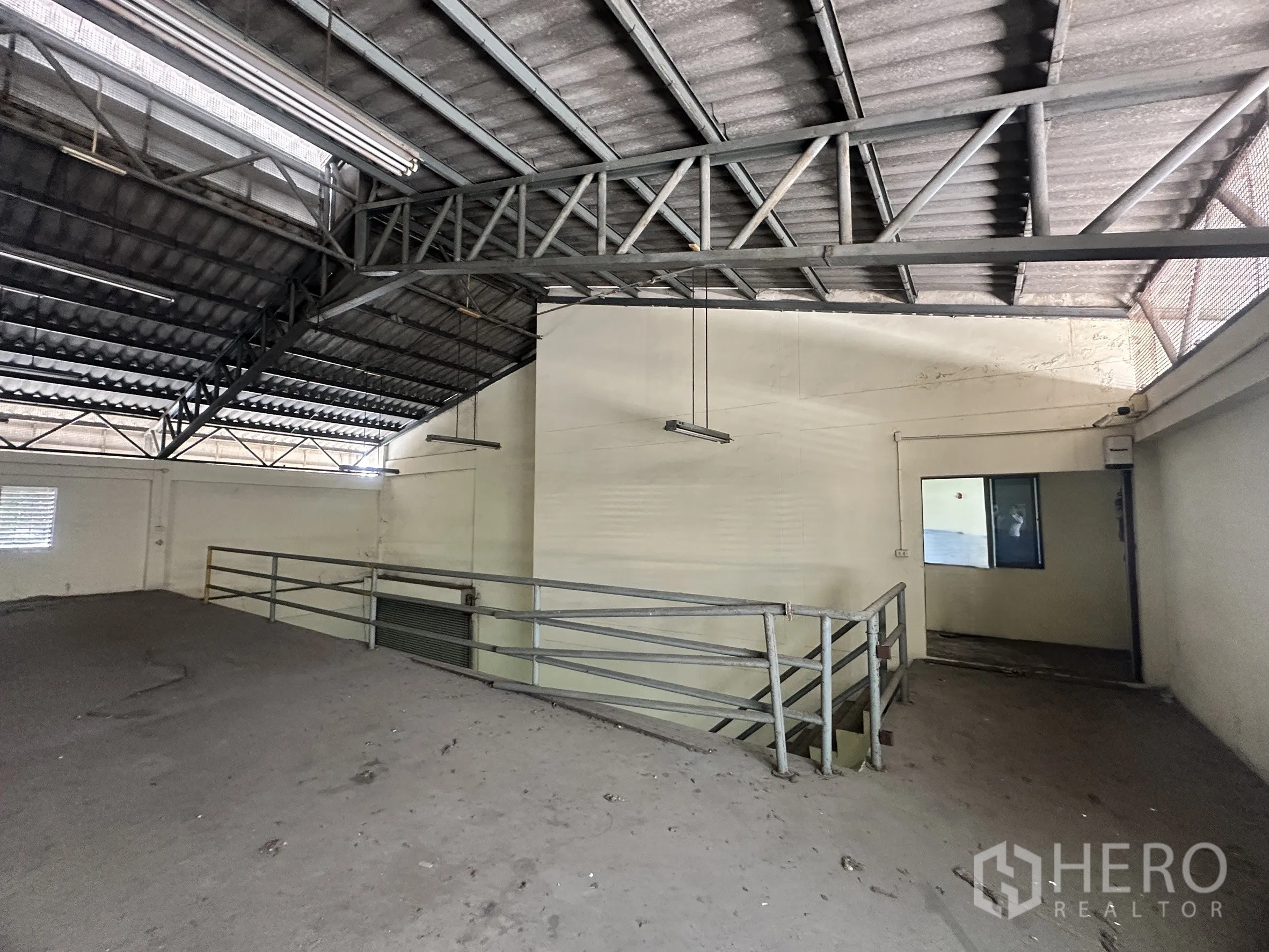 Factory for sale in Bang Bua Thong, Nonthaburi - Metal mezzanine platform under a steel truss roof inside the warehouse.
