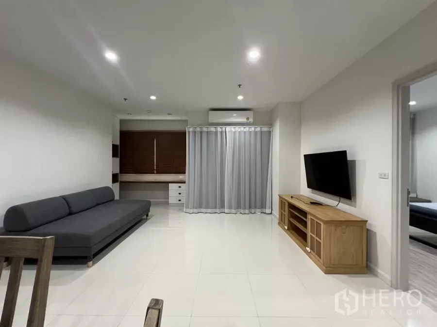 公寓 出租在Bang Kapi, Bangkok - 明亮客厅，灰色沙发、墙挂电视与内置书桌。