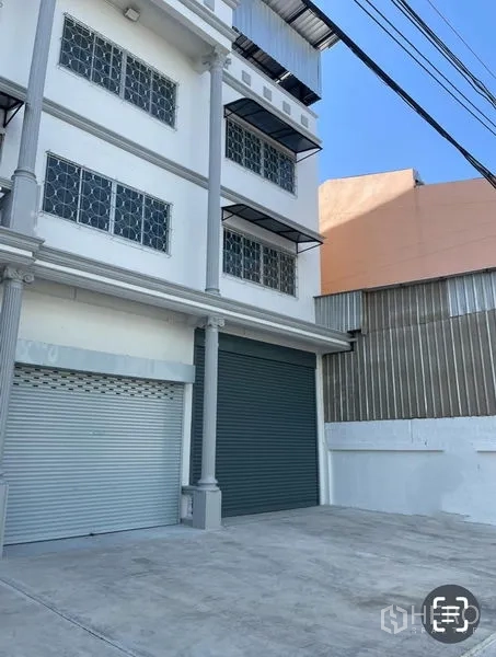 Warehouse for rent in Mueang Samut Sakhon, Samut Sakhon - Street-facing facade of a multi-storey warehouse with dual roller-shutter loading bays and a concrete forecourt.