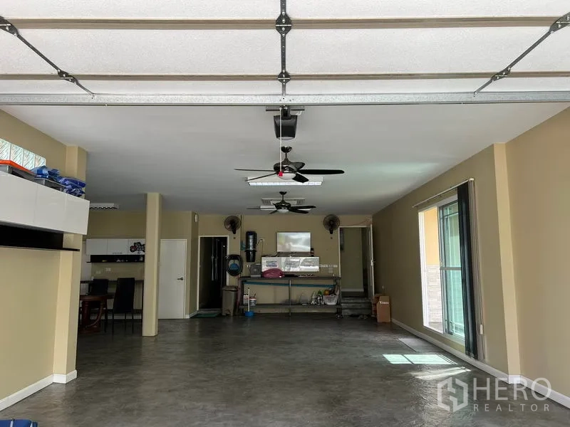 独立式住宅 出租在Bang Kapi, Bangkok - 大面积多功能空间，吊扇、抛光地面与分段式车库门轨道。