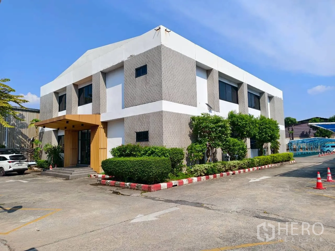 独立物业 for rent in Lak Si, Bangkok - 独栋办公楼转角外观，绿篱与宽阔停车场。