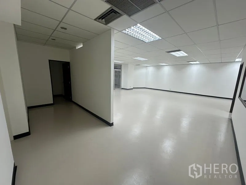 Office Space for rent - Wide corridor leading to an open work area with partial wall divider and ceiling air vents.