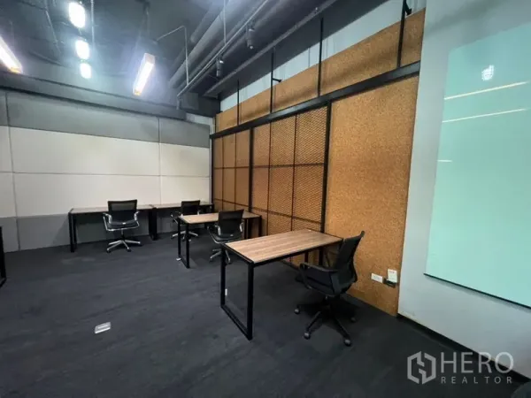 สำนักงาน ให้เช่า - ออฟฟิศแบบเปิดมีผนังตกแต่งลายคอร์ก โต๊ะทำงานหลายจุด และไฟเพดานแบบเส้น