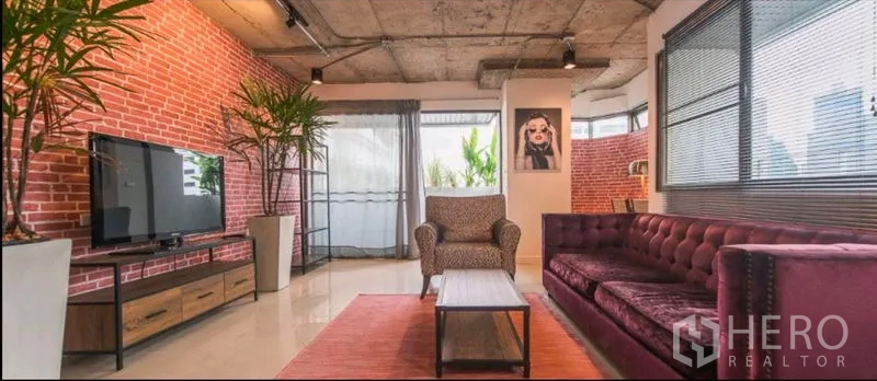 公寓 出租在Watthana, Bangkok - 工业风客厅，混凝土天花与红砖墙，大窗与天鹅绒沙发