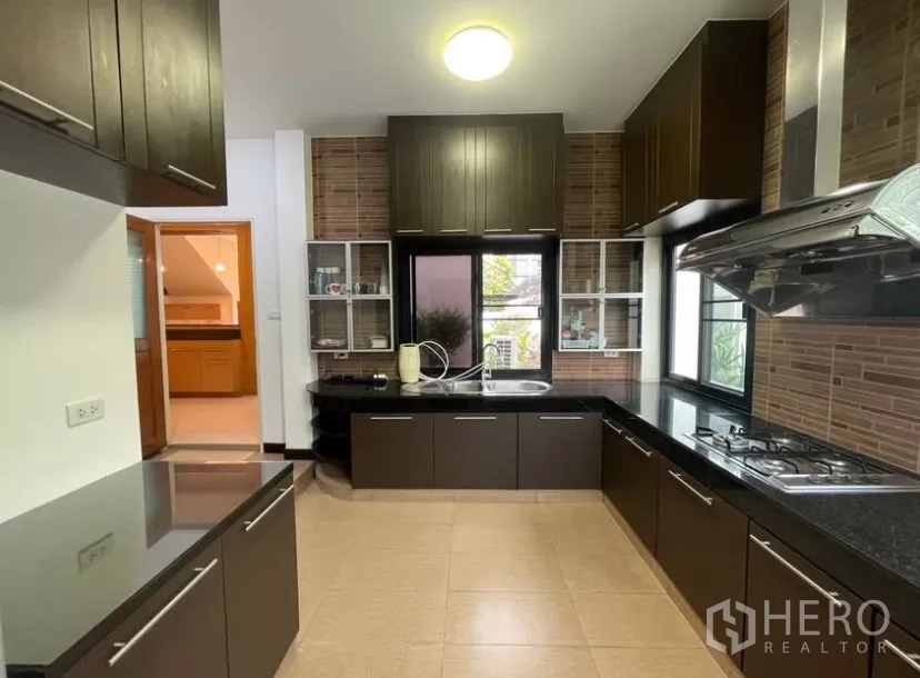 Detached House for rent in Chatuchak, Bangkok - Fully fitted kitchen with dark cabinets, gas hob and black granite countertops.