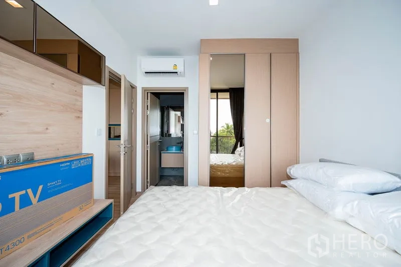 Condominium for rent in Watthana, Bangkok - Bedroom view toward wardrobe and bathroom entrance with mirrored door.