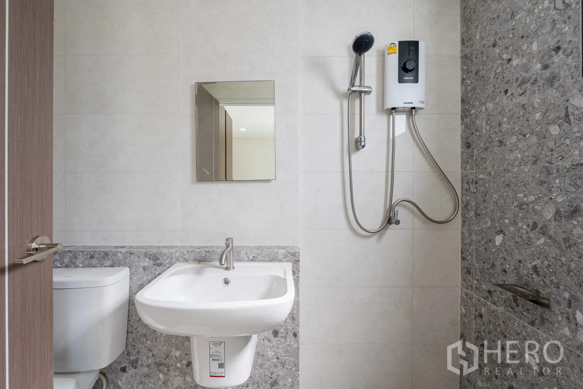 Home Office for rent in Khlong Toei, Bangkok - Bathroom with shower and electric water heater beside a basin and toilet.