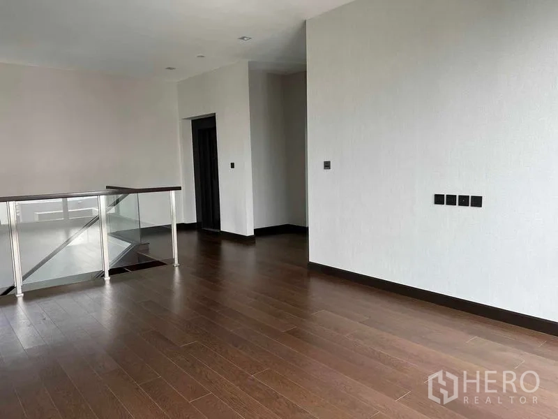 Detached House for sale in Bang Kruai, Nonthaburi - Spacious family room with wood floors and a glass balustrade.