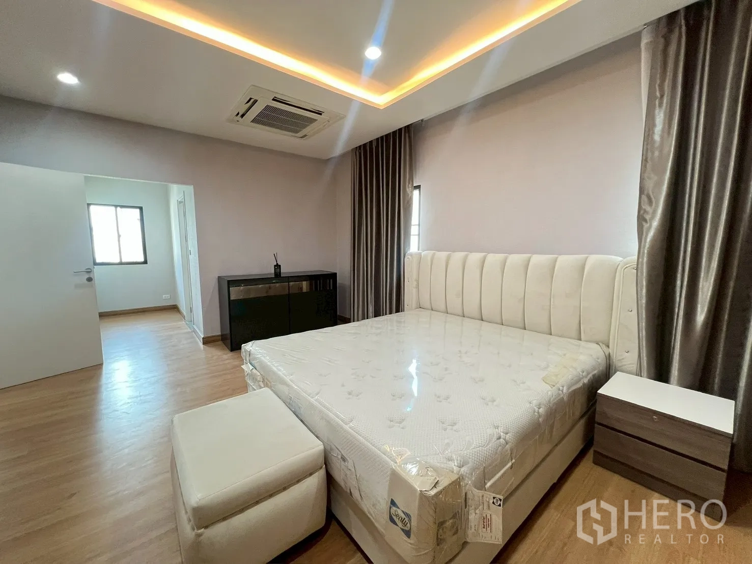 独立式住宅 出租或出售在Bang Phli, Samut Prakan - 宽敞主卧，嵌入式灯带与吊顶空调，窗边放置大床。