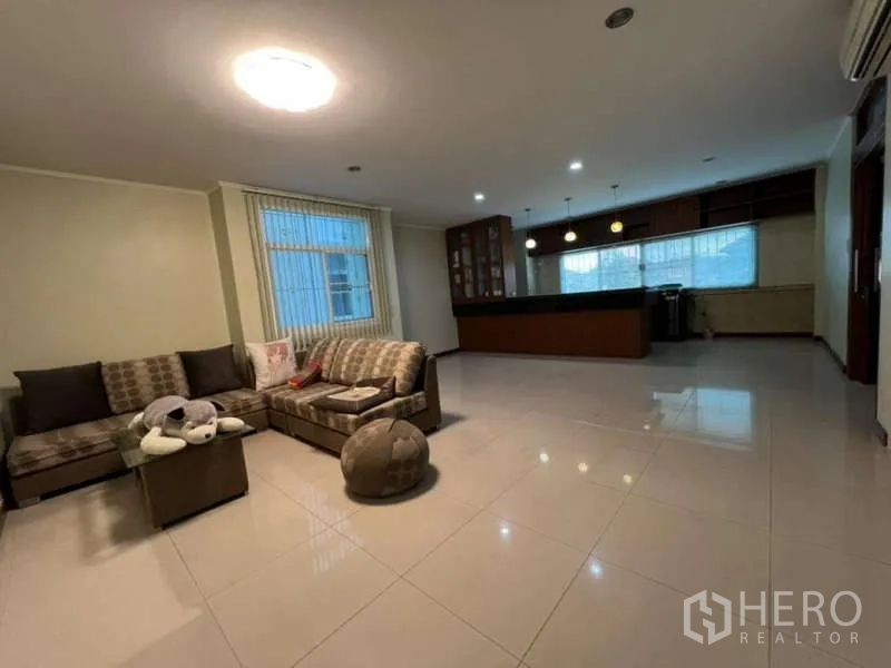 带办公室的家 出租或出售在Min Buri, Bangkok - 开放式起居区，转角沙发、地砖地面，旁接带吧台的厨房。