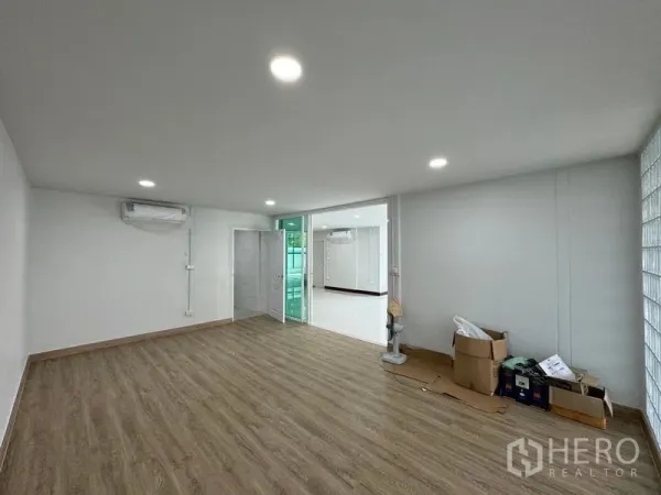 Home Office for rent in Bueng Kum, Bangkok - Air-conditioned room with wood flooring opening to a bright glass-partitioned office area.