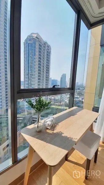 公寓 出租在Khlong Toei, Bangkok - 转角落地窗书桌，俯瞰澎蓬区域的城市天际线。
