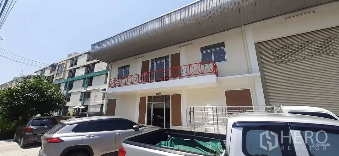 工厂 出租在Bang Sao Thong, Samut Prakan - 翻新工厂外立面，红色阳台栏杆、卷闸门与停车位。