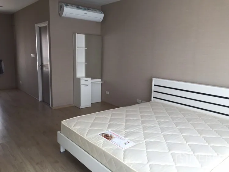 Townhouse for rent in Suan Luang, Bangkok - Spacious bedroom with a white bed, air conditioner, and vanity unit.