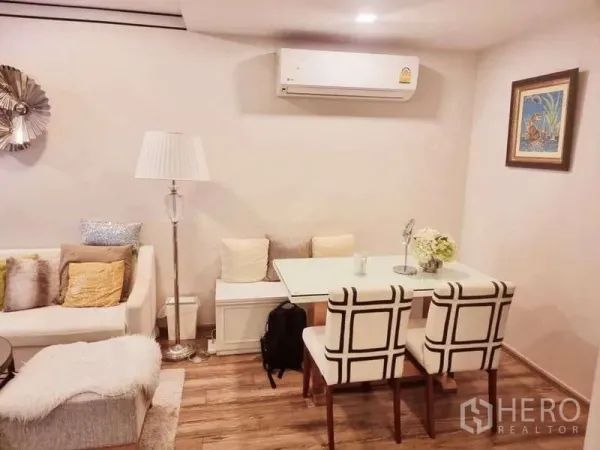 Condominium for sale in Bang Rak, Bangkok - Compact dining nook with bench seating, two upholstered chairs, floor lamp and wall-mounted air conditioner.