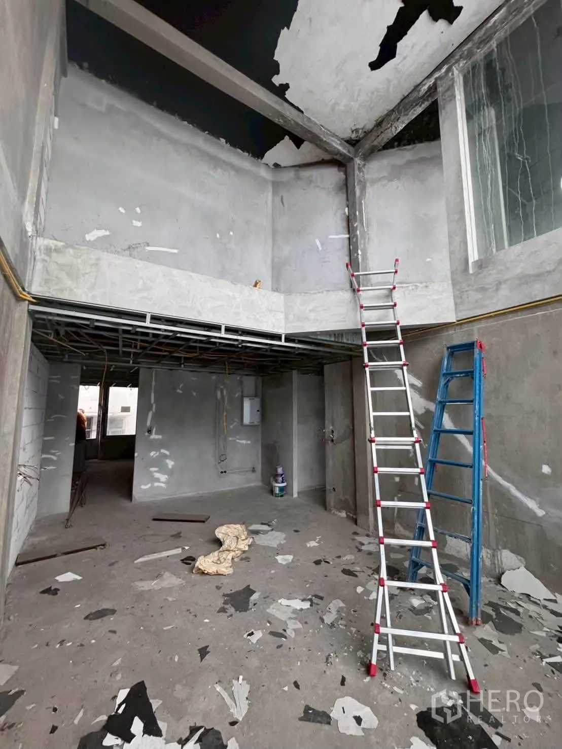 Shophouse for rent in Khlong Toei, Bangkok - Raw double-height interior with mezzanine area, ladders, and exposed concrete.