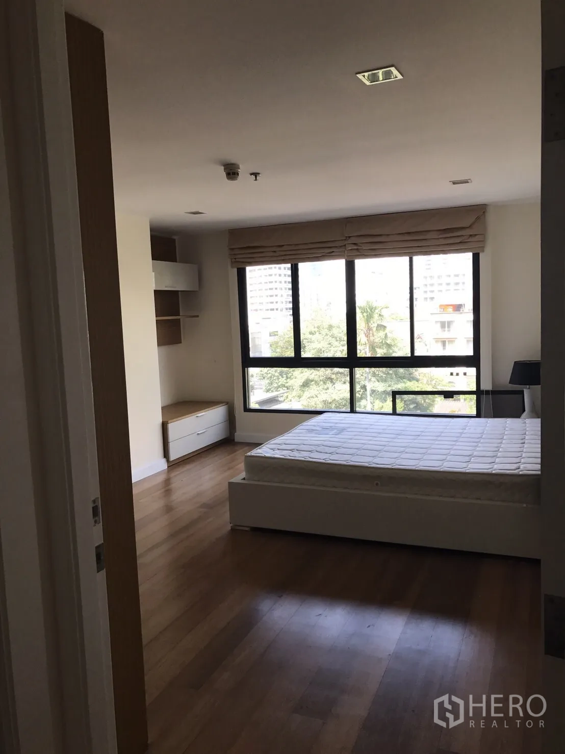 公寓 出租或出售在Watthana, Bangkok - 采光充足的卧室，落地窗眺望绿意，木地板平台床。