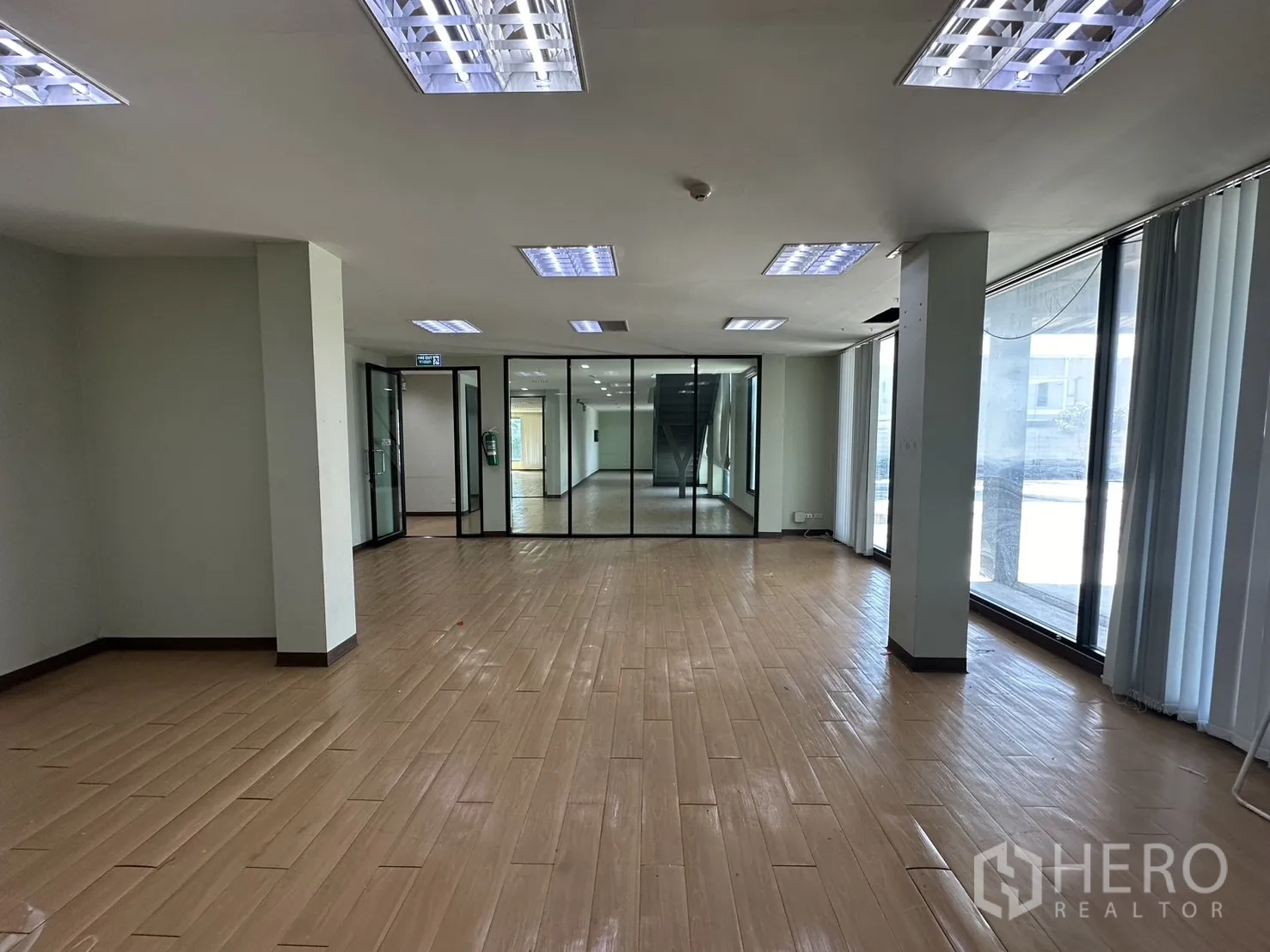 带办公室的家 出租在Prawet, Bangkok - 开放式办公室，玻璃隔断与落地窗面向停车区。