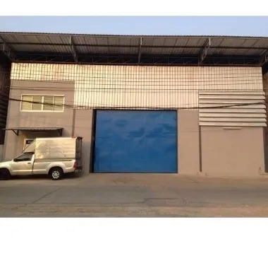 Warehouse for rent in Bang Kapi, Bangkok - Warehouse exterior in Bang Kapi with a large blue loading door, metal roof and easy roadside access.