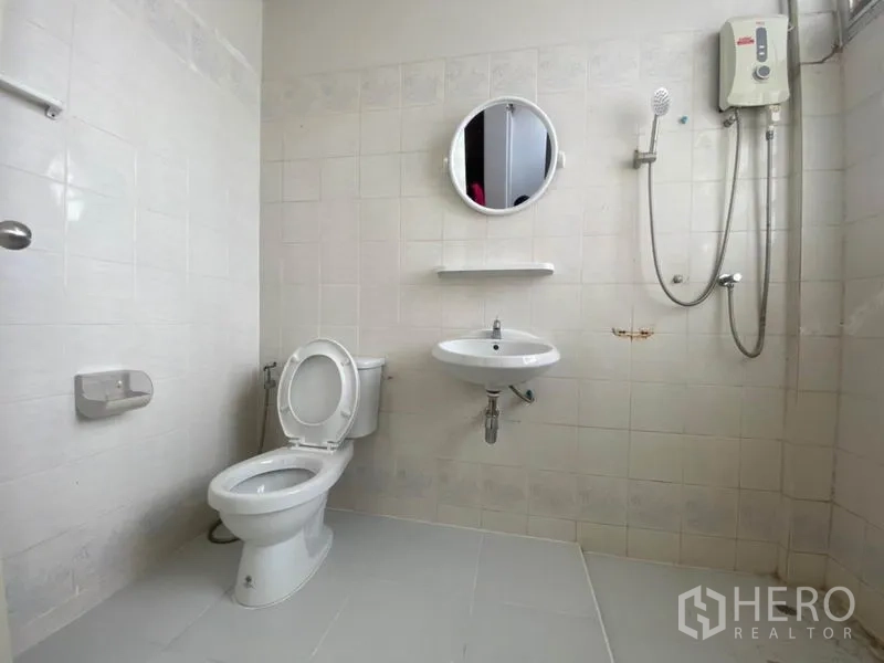 联排别墅 出租在Watthana, Bangkok - 白色瓷砖浴室，淋浴、热水器、圆镜和坐便器。