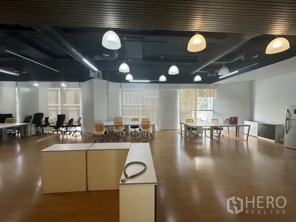 Office Space for rent in Pathum Wan, Bangkok - Open office with pendant lights, exposed ceiling, desks and a pantry area on wood flooring.