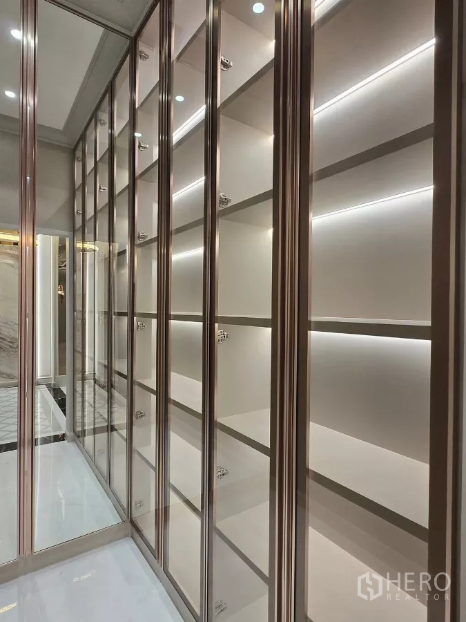 Detached House for rent or sale in Bang Kapi, Bangkok - Glass-fronted display cabinets with LED lighting in a corridor-style storage room.