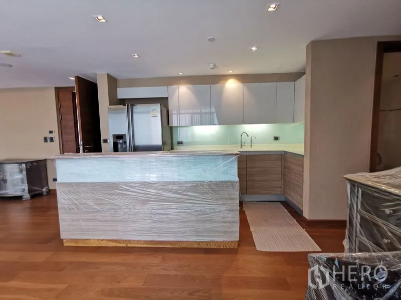 Condominium for rent or sale in Phaya Thai, Bangkok - Contemporary L-shaped kitchen with island, stone countertops, and stainless-steel refrigerator.