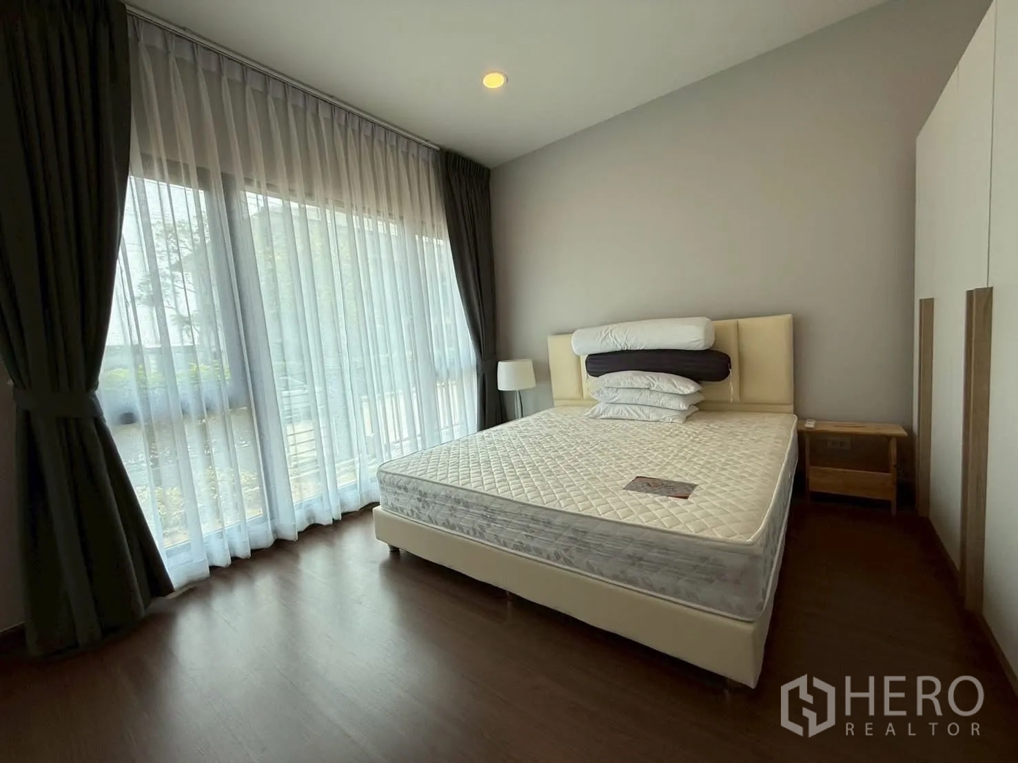 Townhouse for rent - Corner bedroom with full‑height glass, blackout curtains and bedside tables.