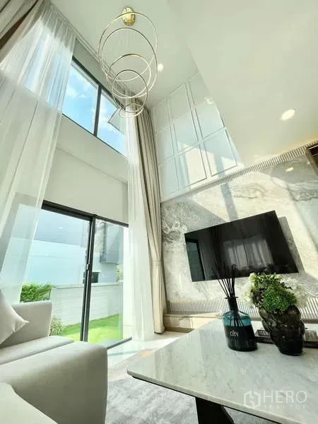 Detached House for rent in Bang Phli, Samut Prakan - Stylish chandelier above a bright living space with tall drapes and garden view.